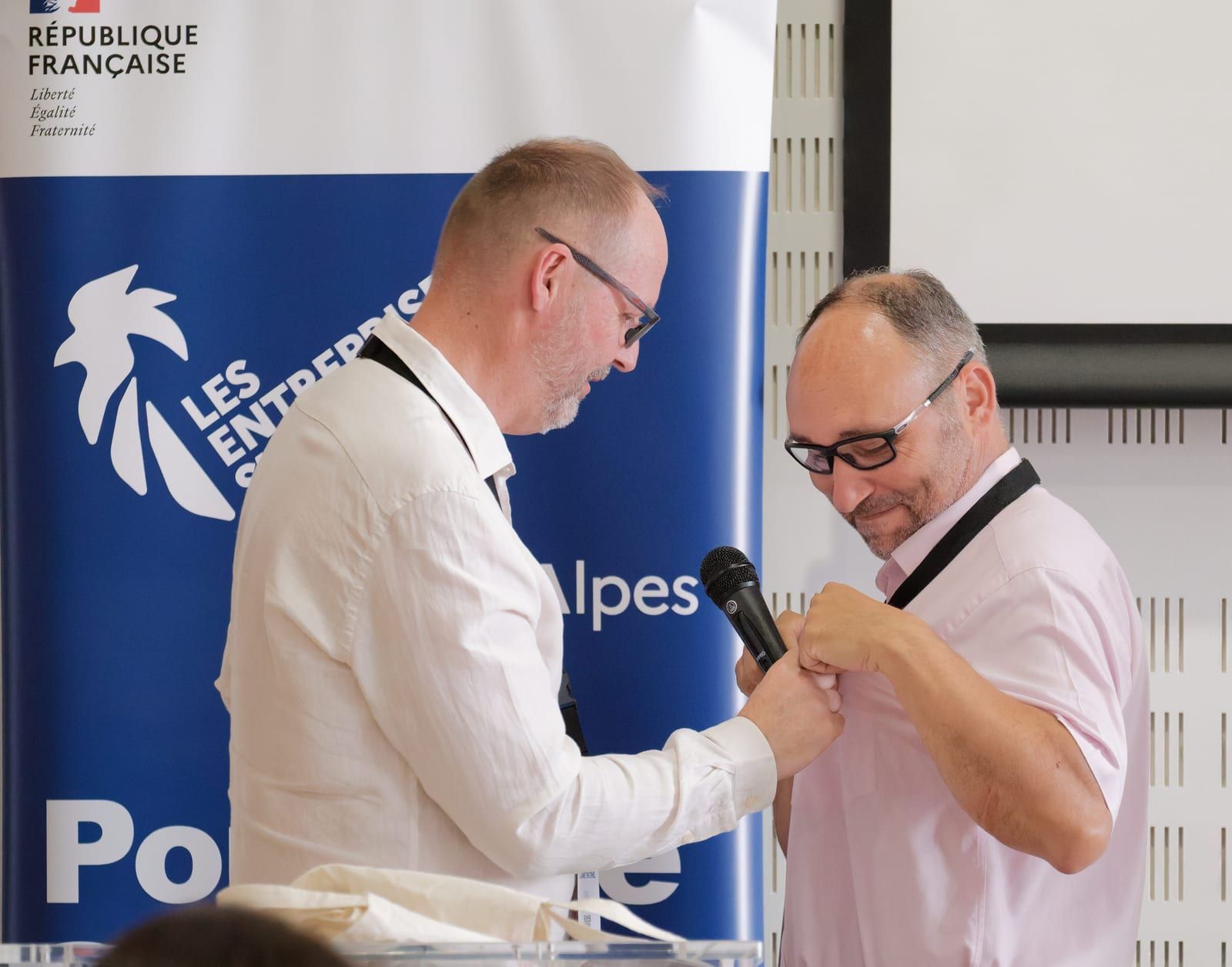 Remise du micro entre deux participants lors d’une rencontre du Club Les Entreprises s’engagent, devant le kakémono du dispositif